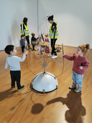 les enfants de la crèche testent les sculptures monumentales et découvrent la musique qu'elles produisent