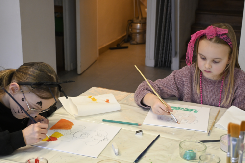 enfants qui peignent un visage de clown sur une toile